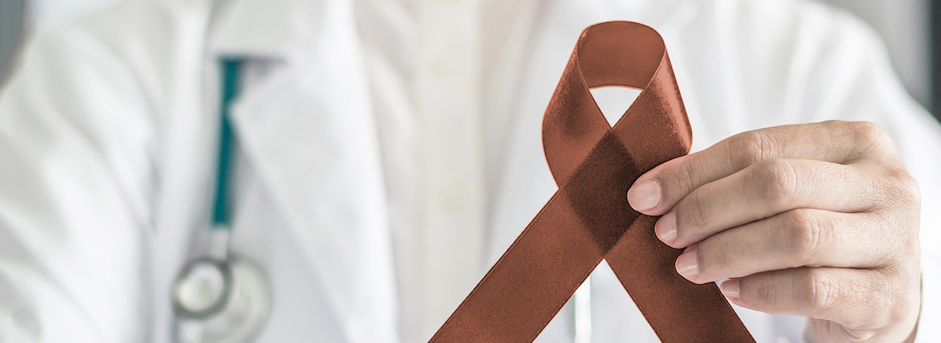 The image features a healthcare professional holding a red ribbon with an A symbol on it against a backdrop of a medical setting, which suggests a theme related to awareness or support for a cause often associated with the red ribbon, such as AIDS awareness.